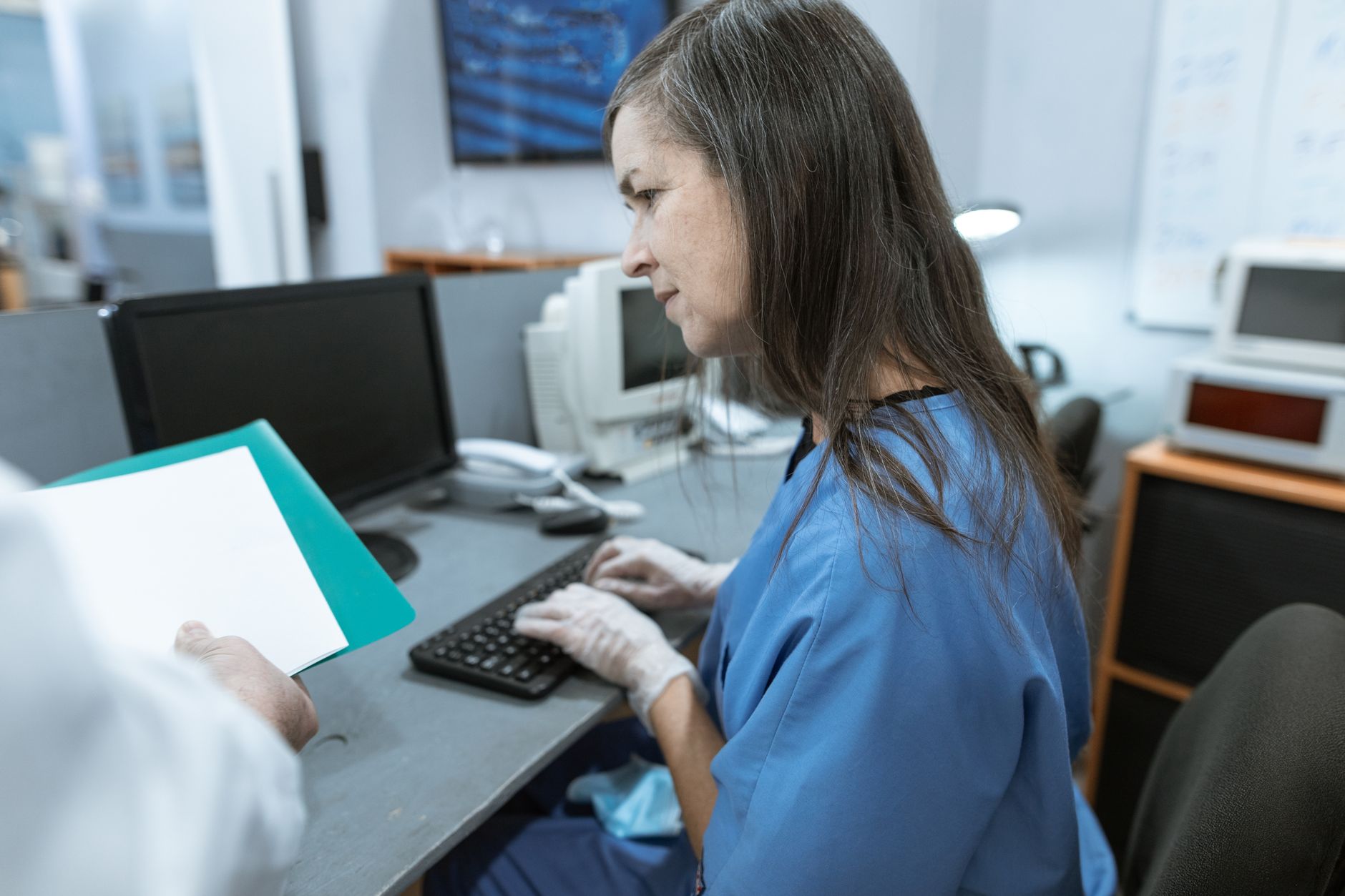 doctor typing patient notes on a computer in a clinic