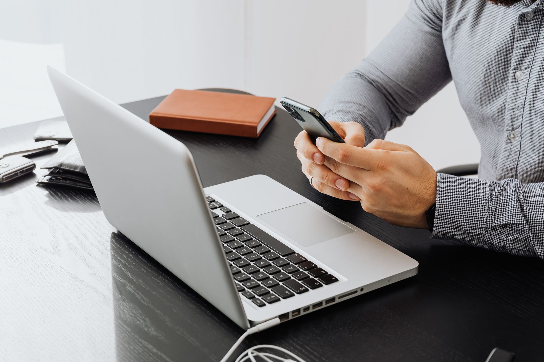 a real estate agent typing on a laptop with a phone in hand at a modern desk