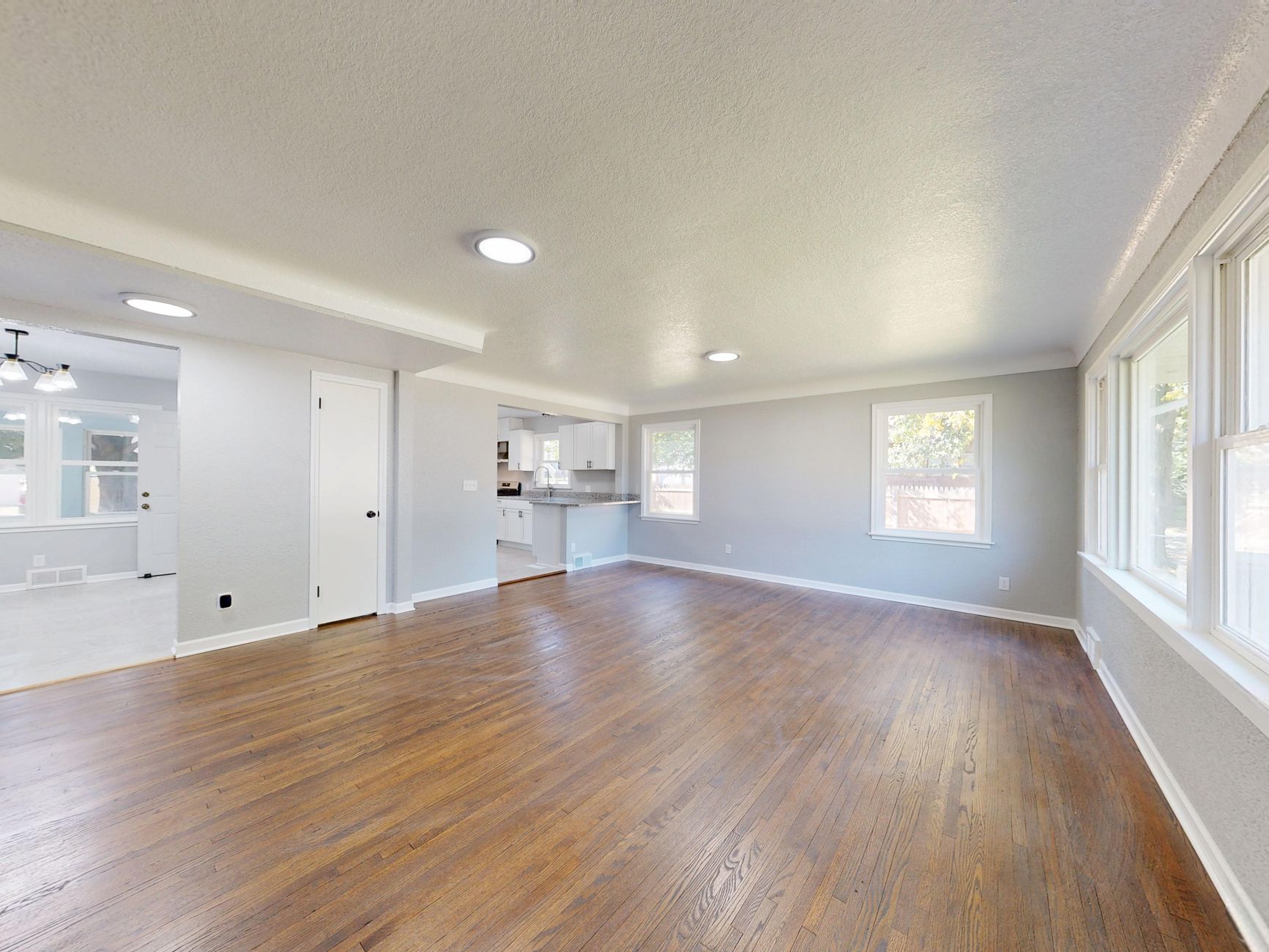 an empty staged living room with natural light and white walls