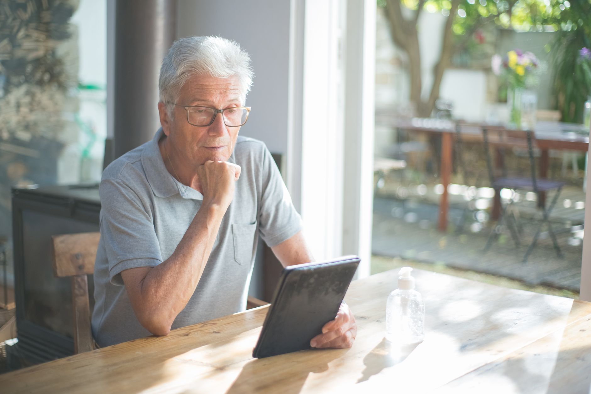 an older man reading a tablet screen with a cup of tea nearby