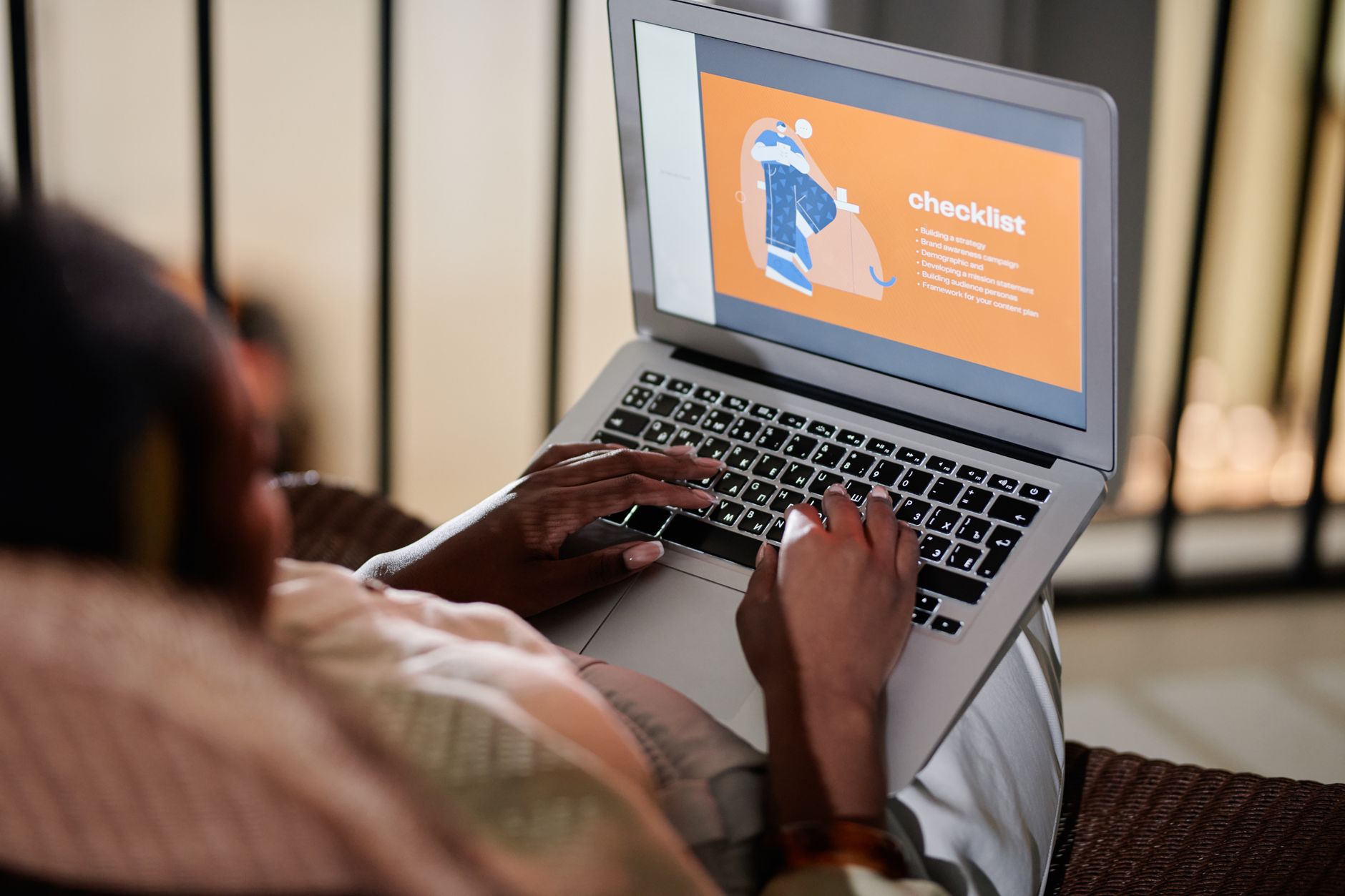Person sitting at a desk reviewing AI-generated text on a laptop with a checklist nearby