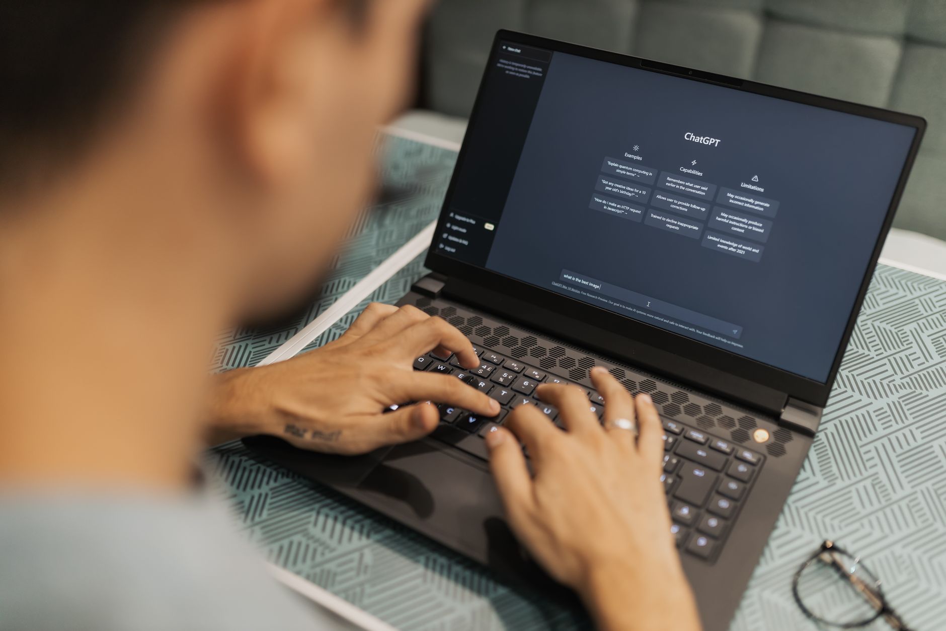 A person typing on a laptop showing an AI chat interface while working on SEO content.